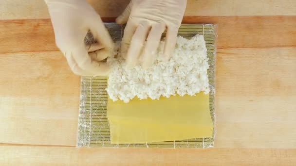 Szef kuchni przygotowuje sushi umieszczając ryżu na glony Nuri - Materiał filmowy, wideo