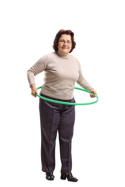Full length portrait of an elderly woman with a hula-hoop isolated on white background - Foto, Imagem