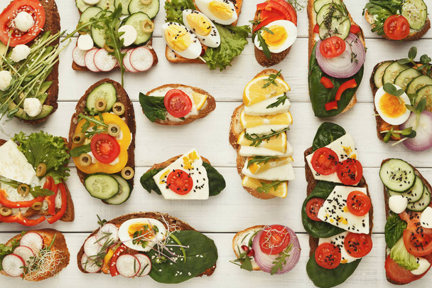 Vielfalt an gesunden vegetarischen Sandwiches auf weißem Holz, Draufsicht - Foto, Bild
