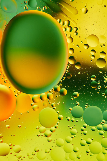 Mixing water and oil, beautiful color abstract background based on green and yellow circles, ovals, macro abstraction - 写真・画像
