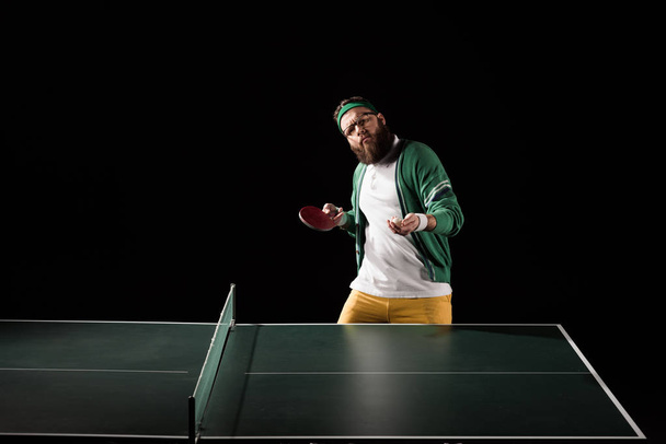 bearded sportsman with tennis equipment standing at table isolated on black - Foto, Imagem