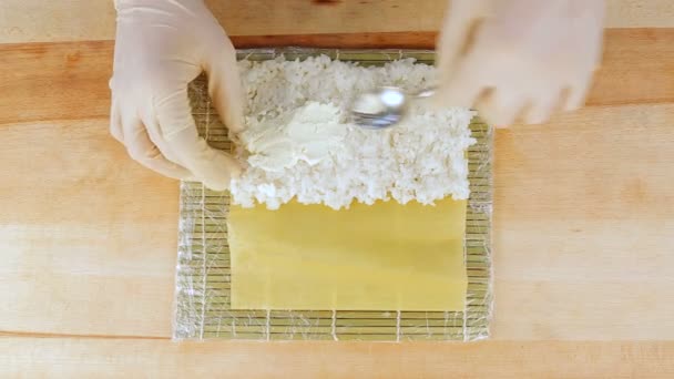 der Koch bereitet Sushi zu, indem er Reis auf die Algennuri legt - Filmmaterial, Video