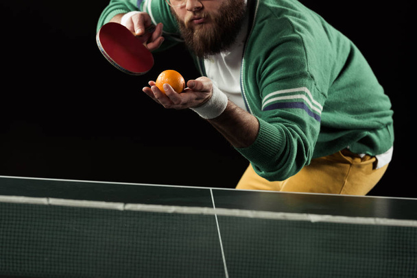 vue partielle du joueur de tennis avec mandarine et raquette de tennis dans les mains isolées sur noir
 - Photo, image