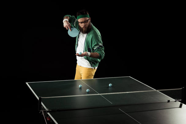 jogador de tênis barbudo praticando em tênis de mesa isolado em preto
 - Foto, Imagem