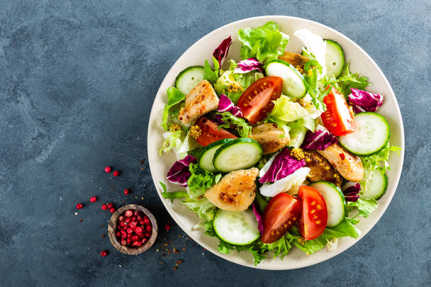 Fresh vegetable salad of tomatoes, cucumbers, italian mix, lettuce and grilled chicken breast. Fried chicken meat, fillet with salad. Healthy food. Flat lay. Top view - Photo, image