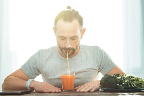 Calm focused man sitting and drinking juice. - Valokuva, kuva