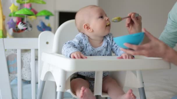 Cute little baby boy, eating mashed vegetables for lunch, mom feeding him, sweet toddler boy, smiling - Materiał filmowy, wideo