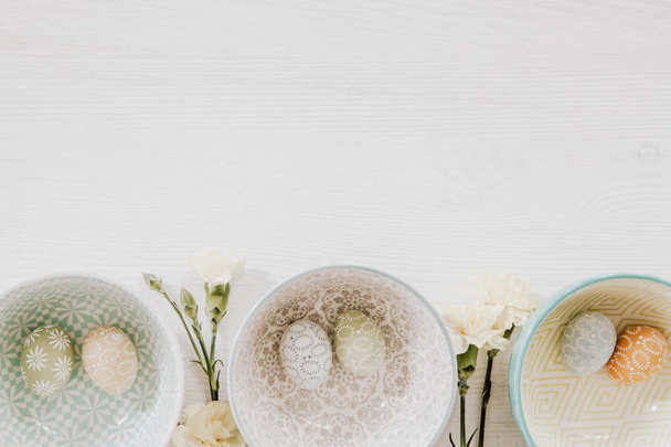 Easter eggs in decorative bowls and gillyflowers on the bottom o - Photo, Image