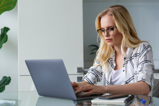 mujer rubia joven usando el ordenador portátil mientras trabaja en casa
 - Foto, imagen