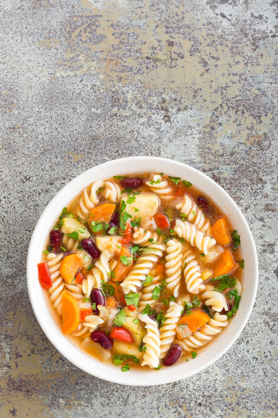 Minestrone soup. Vegetable soup with fresh tomato, celery, carrot, zucchini, onion, pepper, beans and pasta. Dish of italian cuisine. - Foto, Imagen