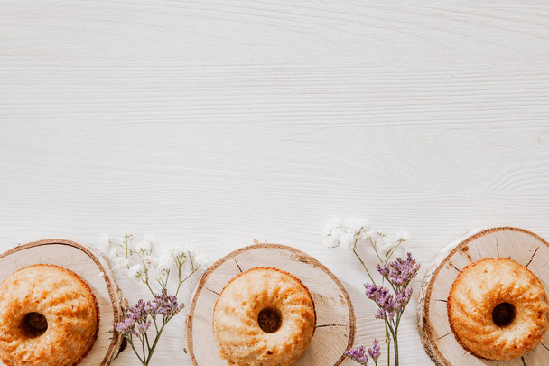 Houten blokken met cupcakes, paarse en witte bloemen op het bot - Foto, afbeelding
