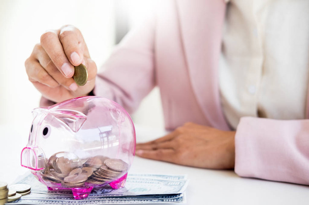 Close up of Businessman putting coin into small piggy bank , The - Photo, Image