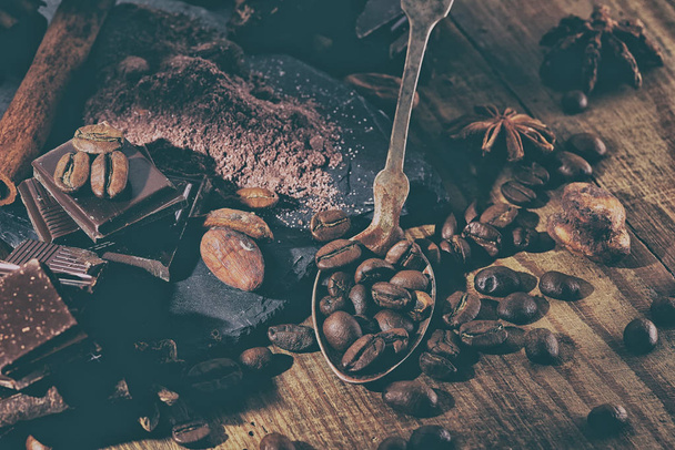 Chocolate negro roto, cacao en polvo y granos de café en una mesa de madera
 - Foto, imagen