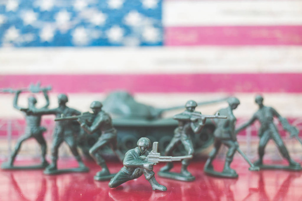 Miniatuur speelgoed soldaten in de slag bij scène met Amerikaanse vlag achtergrond - Foto, afbeelding