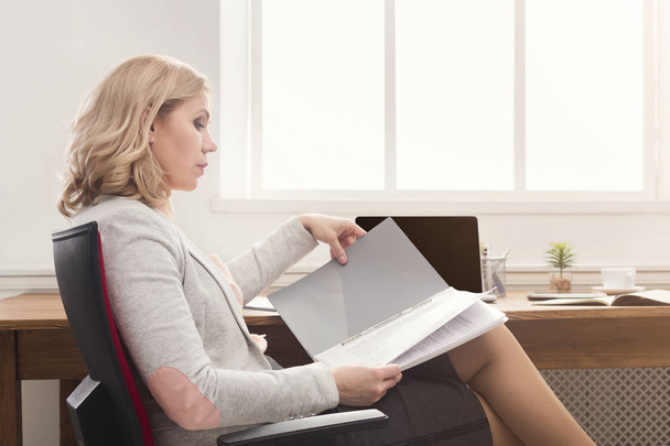 Businesswoman reading document at office desktop - Fotoğraf, Görsel