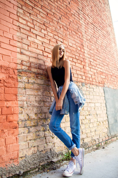 fashion girl standing near brick wall in denim and sneakers. Vogue Style - Фото, изображение