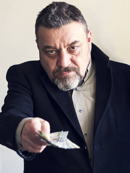 Bearded man in a black suit gives money. Corruption. Illegal operations - Fotó, kép