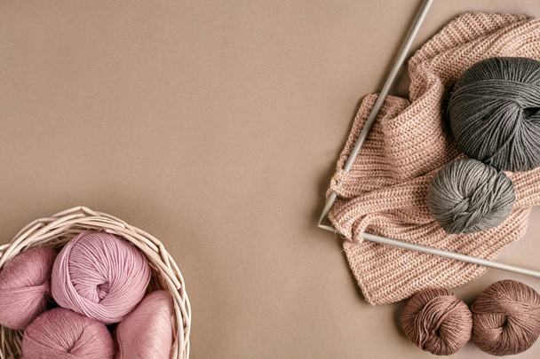 Des boules de laine mérinos, tricotées sur des aiguilles à tricoter sur une surface beige. Vue du dessus
 - Photo, image