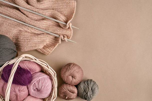 Des boules de laine mérinos, tricotées sur des aiguilles à tricoter sur une surface beige. Vue du dessus
 - Photo, image