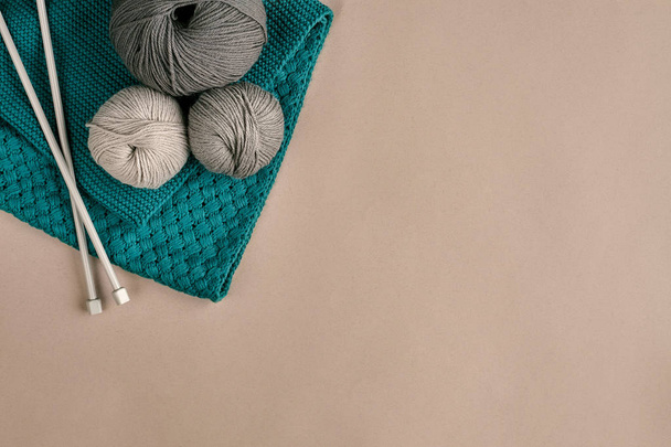 Grijs en turquoise wol brei- en breien op naalden op beige achtergrond. Bovenaanzicht. Kopiëren van ruimte - Foto, afbeelding