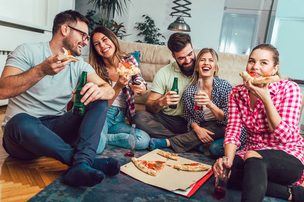 Grupo de jóvenes amigos comiendo pizza.Fiesta en casa.Concepto de comida rápida
. - Foto, imagen