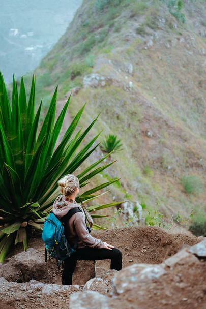 Mujer con mochila en la ruta de trekking cerca del borde de la montaña mirando hacia el valle. Isla de Santo Antao, Cabo Verde
 - Foto, imagen