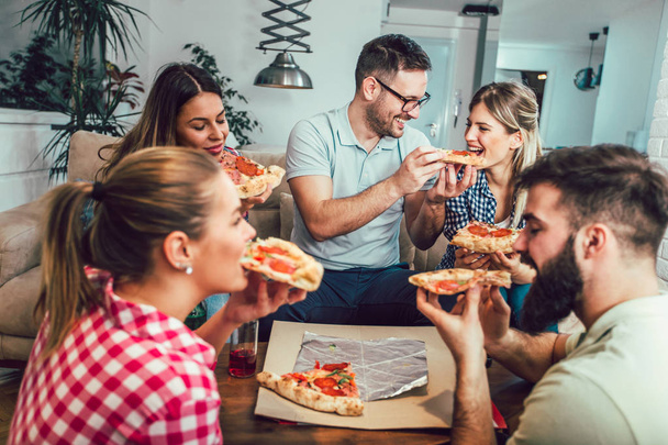 Pizza yiyen bir grup genç arkadaş. Ev partisi. Fast food konsepti.. - Fotoğraf, Görsel