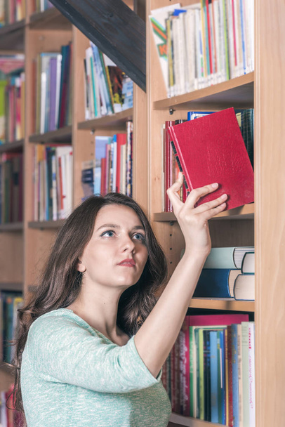 Девушка выбирает книгу из библиотеки
 - Фото, изображение