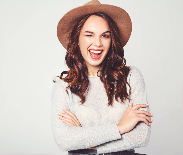 Portrait of young stylish laughing girl model in gray casual summer clothes in brown hat with natural makeup isolated on gray background. Looking at camera and winking - Zdjęcie, obraz