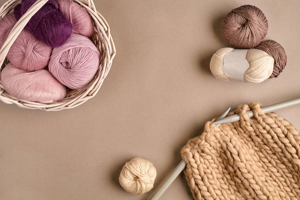Laine à tricoter rose et marron et aiguilles à tricoter sur fond beige. Vue de dessus. Espace de copie
 - Photo, image