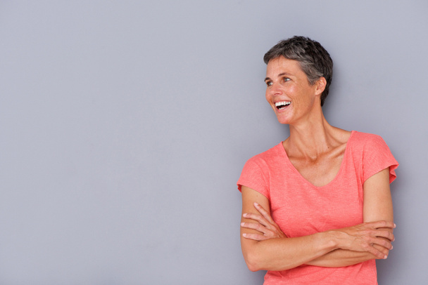 Portrait of laughing older woman against gray wall - Photo, Image