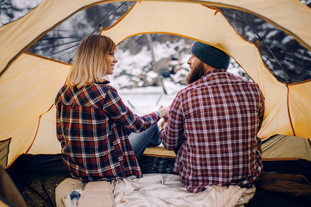 若いカップルが座っているし、冬の間にテントの中で笑顔をハイキングします。Vi をバックアップします。 - 写真・画像