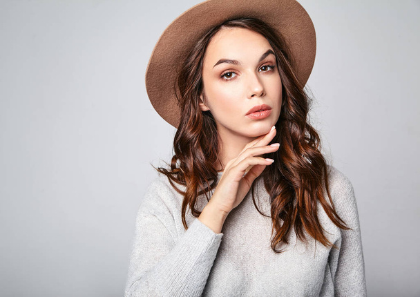 Horizontal portrait of stylish attractive female model wears summer clothes and brown hat with natural makeup posing on gray background in studio. Looking at camera - Foto, afbeelding