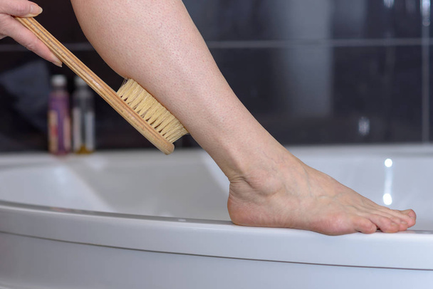Mujer fregando su pierna con un cepillo
 - Foto, Imagen