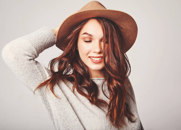 Portrait of young stylish laughing girl model in gray casual summer clothes in brown hat with natural makeup and long blowing hair isolated on gray background. Looking at camera - Φωτογραφία, εικόνα