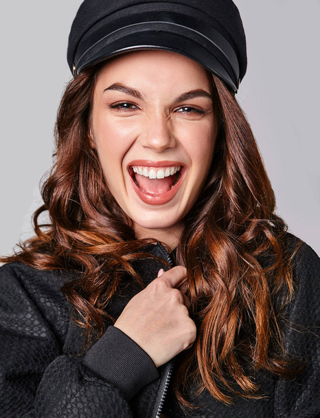 Portrait of young stylish laughing girl model in black casual summer clothes in cap with natural makeup isolated on gray background. Looking at camera - Φωτογραφία, εικόνα