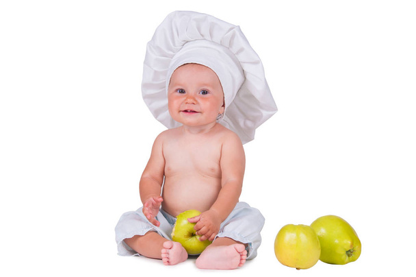 Cheerful little child with apples in hands in a chef suit on a white background. - Zdjęcie, obraz