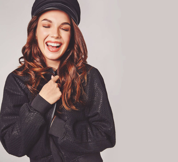 Portrait of young stylish laughing girl model in black casual summer clothes in cap with natural makeup isolated on gray background. Looking at camera - Φωτογραφία, εικόνα