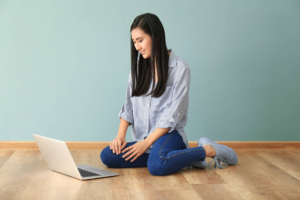 Young Asian woman using laptop on floor indoors - Фото, изображение