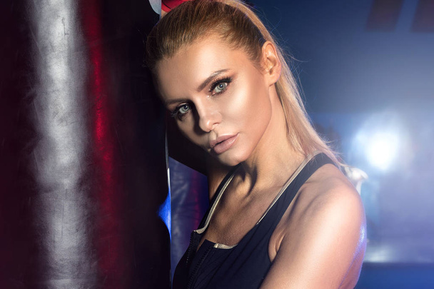 Female boxer posing with punching bag. - Foto, Bild
