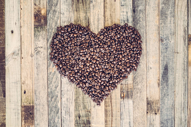 Chicchi di caffè a forma di cuore su sfondo di legno
 - Foto, immagini