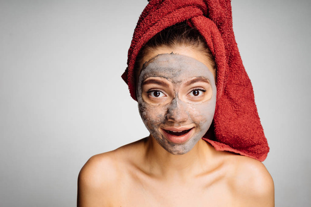 lovely young girl with a red towel on her head has put a useful mask on her face, day spa - Foto, imagen