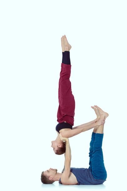 Young athletic couple practicing acroyoga. Balancing in pair - Foto, imagen