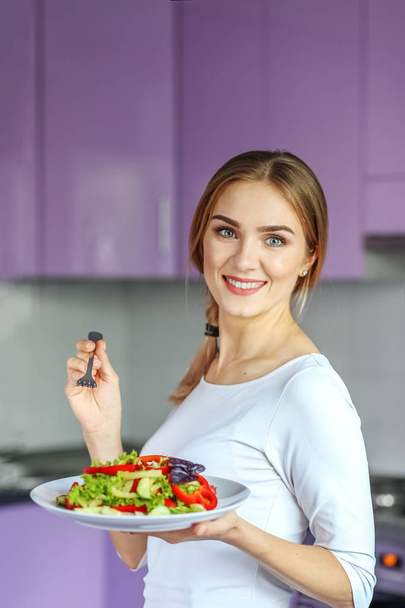 Smiling young girl eating vegetable salad. The concept is health - Fotografie, Obrázek