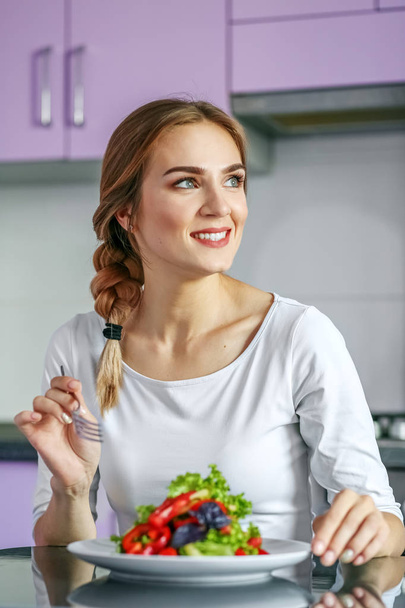 Uma mulher feliz sorrindo come uma salada de legumes saudável. A arrogância
 - Foto, Imagem