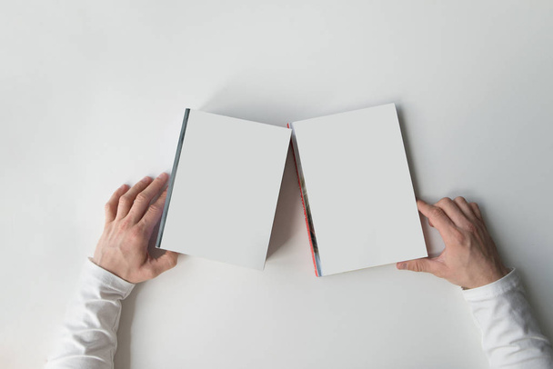 Hands hold white books on a light background. White books with hands on a white table. Flat lay. - Foto, Imagem
