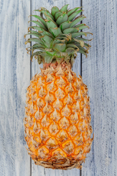 один большой целый ананас на светлом деревянном фоне с копирайтом
 - Фото, изображение