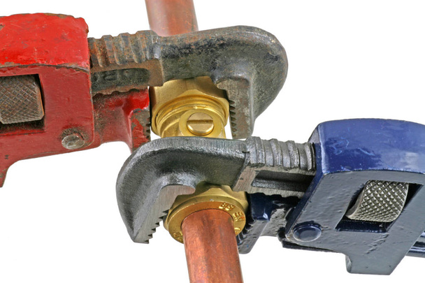 Loodgieter aanscherping leidingen twee Verstelbare moersleutels aanscherping van een Knelkoppeling op 15mm koperen leidingen op een afgelegen witte achtergrond - Foto, afbeelding
