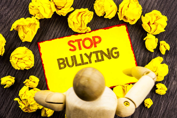 Writing text showing  Stop Bullying. Business photo showcasing Awareness Problem About Violence Abuse Bully Problem written on Sticky Note Holding By Sculpture on the wooden background - Foto, Imagen