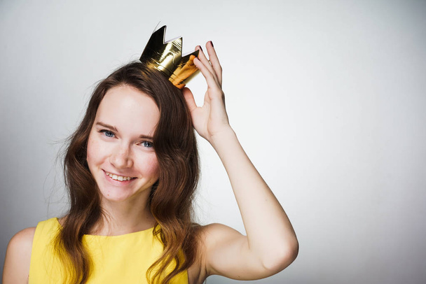 beautiful happy young girl in yellow dress, on head wearing golden crown, smiling, celebrating Mother's Day - Photo, image
